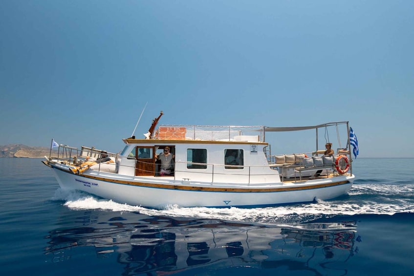 A white boat with a blue stripe, a Greek flag, and a lifebuoy on the deck. 4