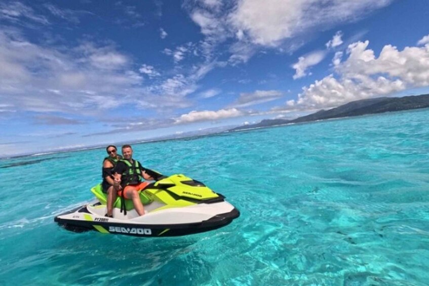 Two people on a jet ski in turquoise water with a clear sky and distant land. 4