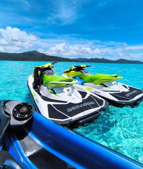 A pair of jet skis on clear turquoise water with a mountainous landscape in the background. 3