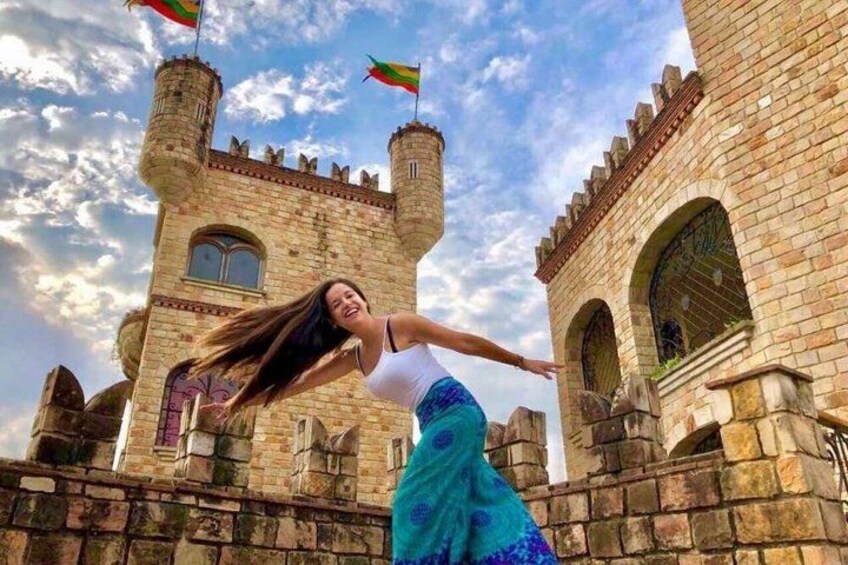 A castle with two towers, a person in a blue skirt, and a clear sky. 1