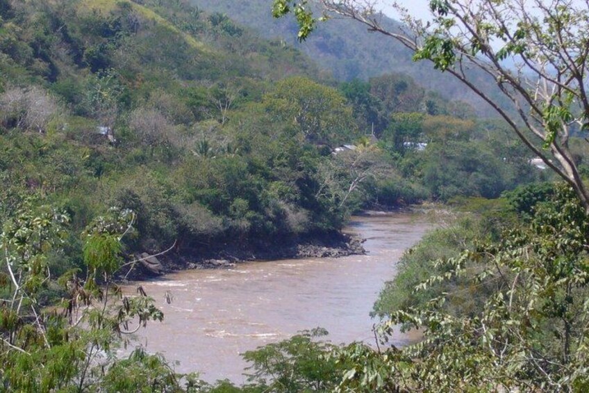 A river flowing through a densely vegetated valley with hills in the background. 5