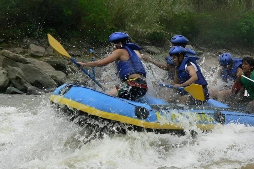 A group of people in a blue and yellow raft navigating through a river with rapids. 4