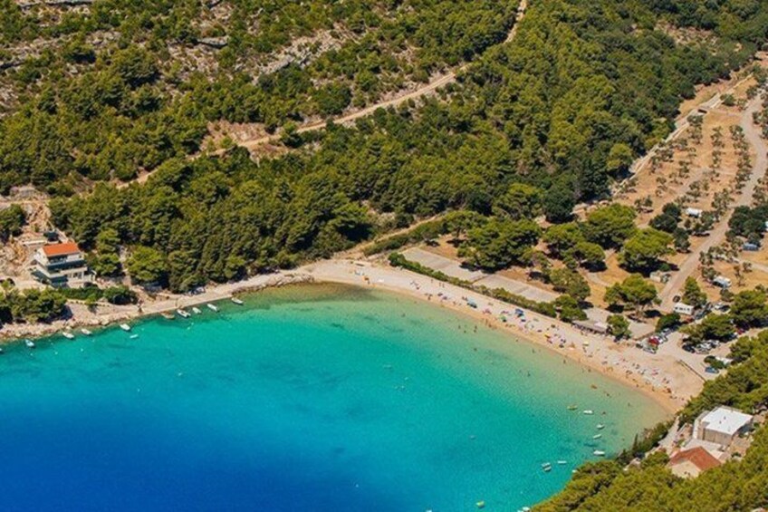 A coastal area with a beach, boats, and a forested hill. 4