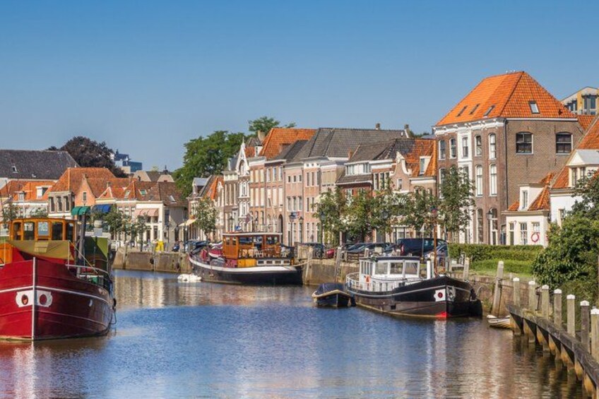 A canal with boats, historic buildings, and a clear sky. 5
