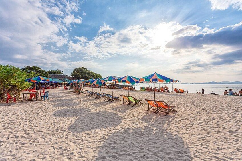 A beach with umbrellas, lounge chairs, and people relaxing. 4