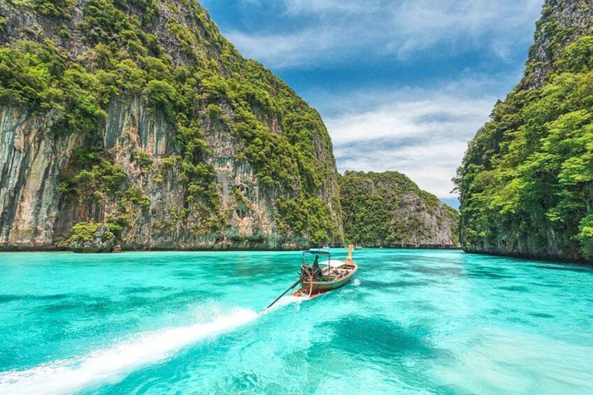 A boat on turquoise water surrounded by lush green cliffs. 2