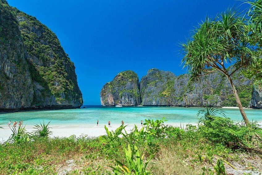 A beach with clear turquoise water, rocky cliffs, and lush greenery. 1