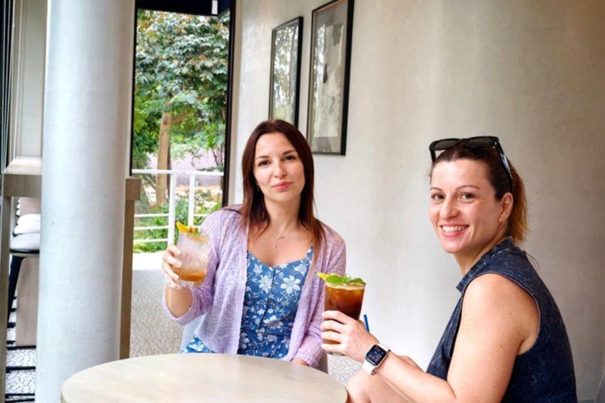 Two people sitting at a table with drinks, a window, and a door in the background. 4