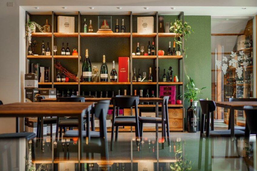A bar with wooden shelves filled with bottles, a green wall, and a glass table. 4