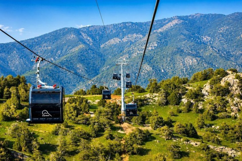 A cable car system in a mountainous area with lush greenery and rocky terrain. 3