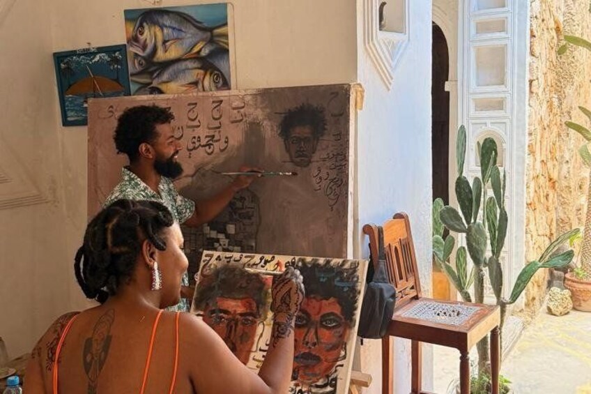 A person painting on a canvas in a room with a cactus and a door. 5