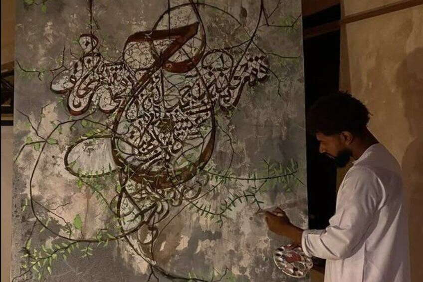 A person painting a wall with Arabic calligraphy. 3