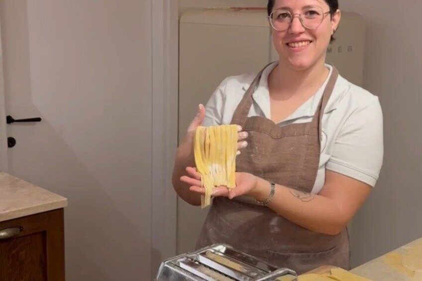 A person holding a long, thin, yellow object, possibly food, in a kitchen setting with a door and a countertop. 1