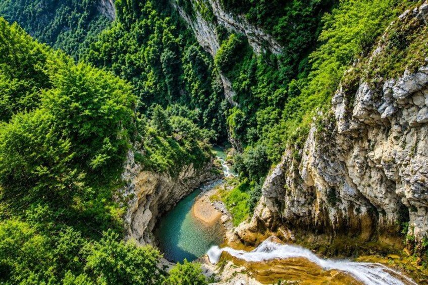 A canyon with a river flowing through it, surrounded by dense green vegetation. 4