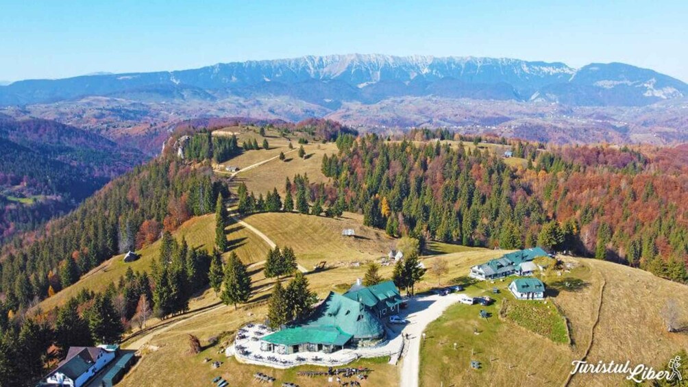 Eine gebirgige Landschaft mit einem großen Gebäudekomplex, umgeben von Wäldern und Feldern. 1