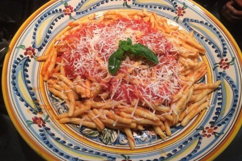 A plate of spaghetti with tomato sauce and grated cheese, garnished with a basil leaf. 3
