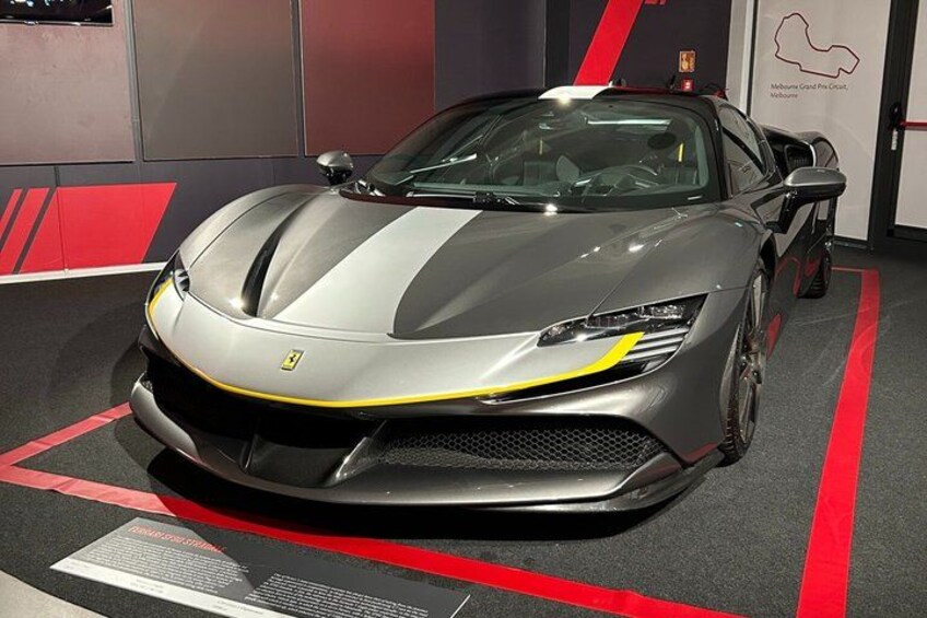 A silver sports car with yellow stripes parked indoors. 5