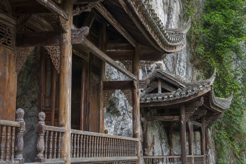 A traditional wooden structure with intricate carvings and a stone wall backdrop. 5