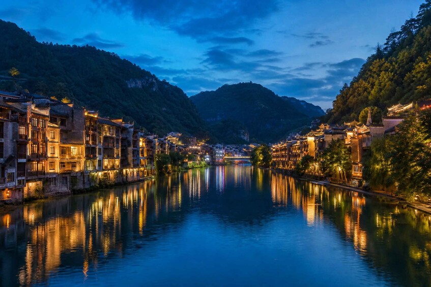 A river reflecting buildings and mountains at dusk. 4