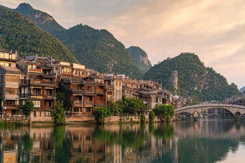 A traditional Chinese village with multi-story buildings, a river, and a stone bridge. 3