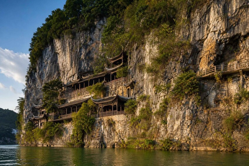 A traditional Chinese pagoda built into a cliffside, overlooking a calm body of water. 2