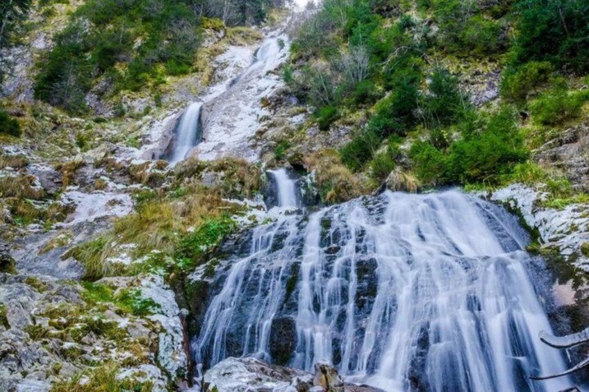 A waterfall cascading over rocks in a forested area. 3