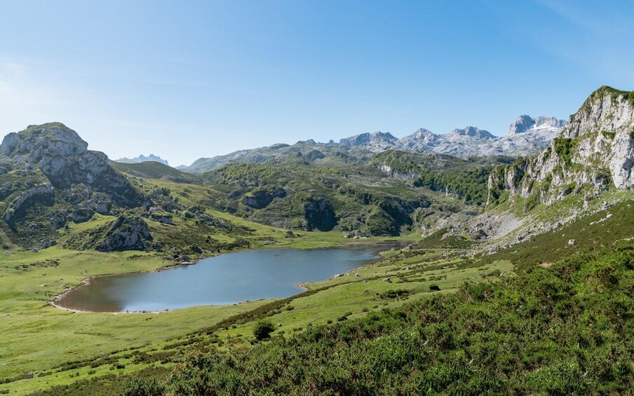 Un paisaje montañoso con un lago rodeado de colinas verdes y acantilados rocosos. 3