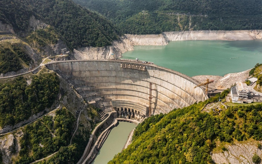 A large dam with a reservoir, surrounded by forested hills. 1