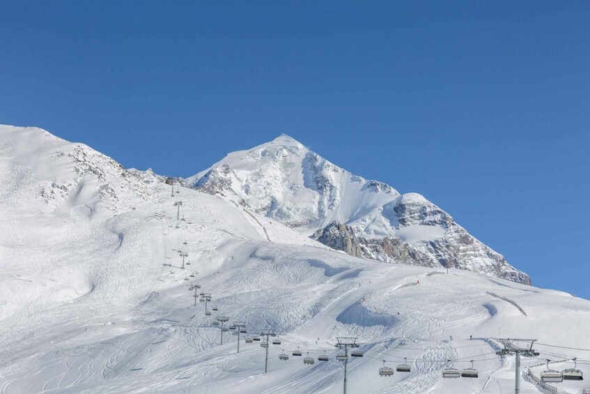 A snow-covered mountain with ski lifts and tracks. 3