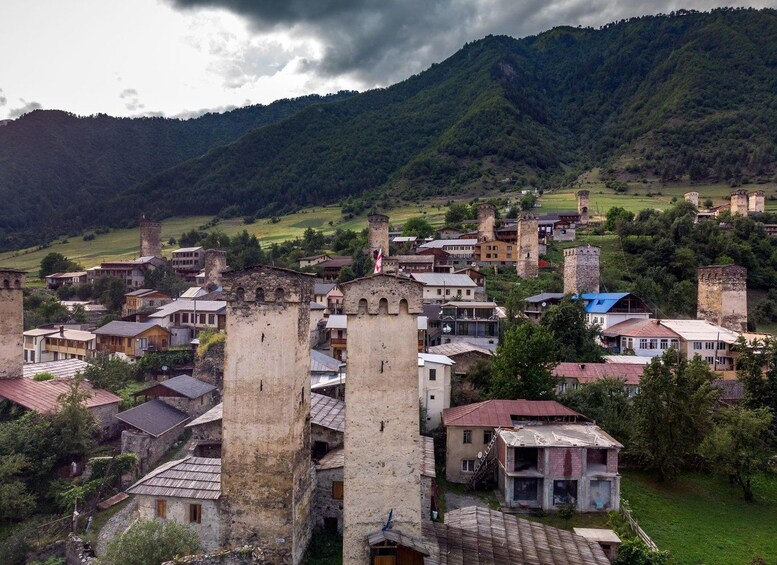 A historic town with medieval towers and buildings nestled in a valley surrounded by mountains. 5