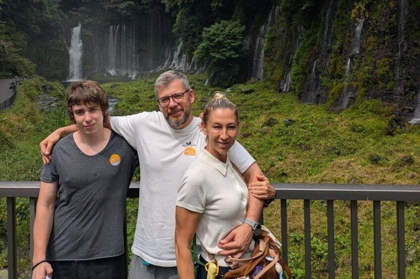 A family standing by a waterfall with lush greenery in the background. 3