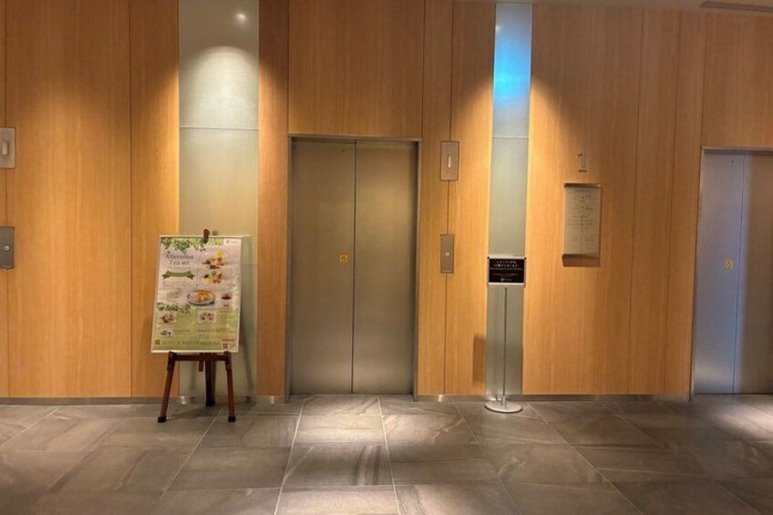 An elevator with a menu stand in a wooden-finished lobby. 5