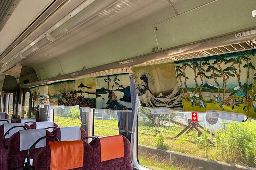 A train interior with seats, a mural, and a view of the outside. 4