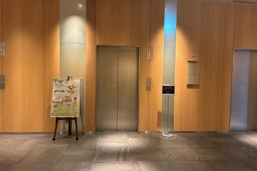 An elevator with a menu stand in a wooden-finished lobby. 3