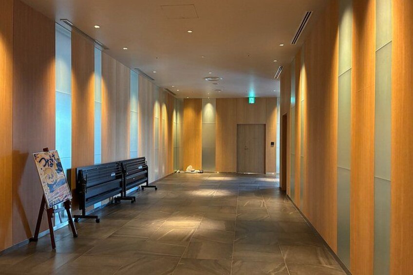 A hallway with wooden panel walls, a bench, and a poster on the left. 2