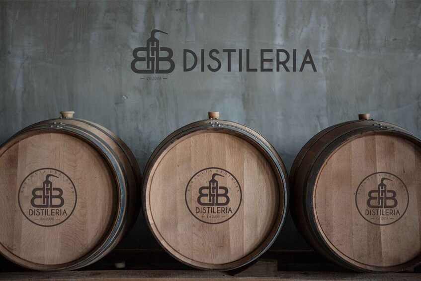 Kolme puista tynnyriä, joissa on seinässä logo «Distileria» ja teksti «Est. 2008». 1