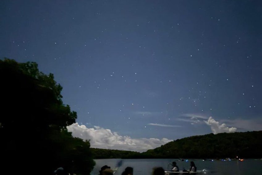 A night sky over a lake with stars and a few clouds. 5