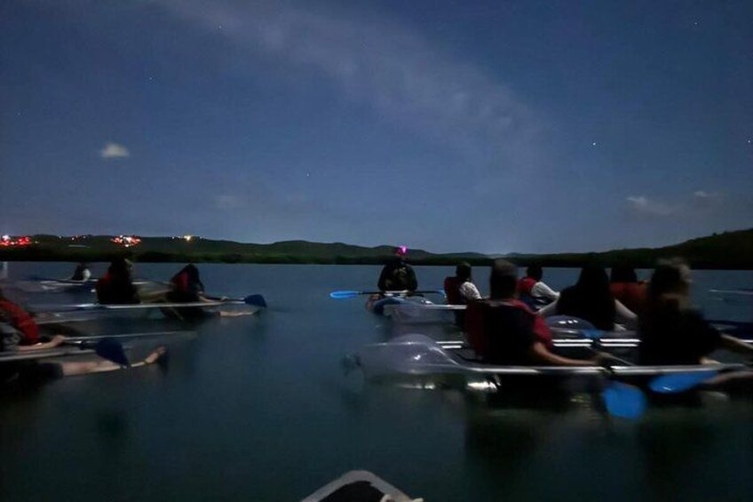 People on a calm body of water, possibly a lake, at night. 4
