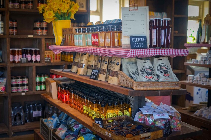 A variety of food products on shelves, including jars, bags, and bottles, with a price list visible. 2