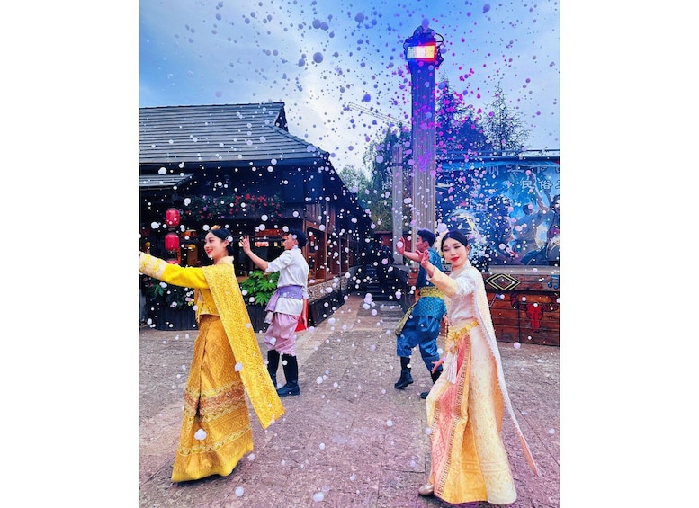 A group of people in traditional attire dancing in an outdoor setting with a building and a tower in the background. 3