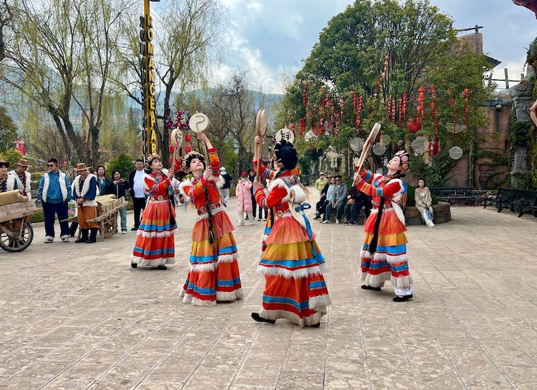 A group of performers in traditional costumes dancing with props in an outdoor setting. 1