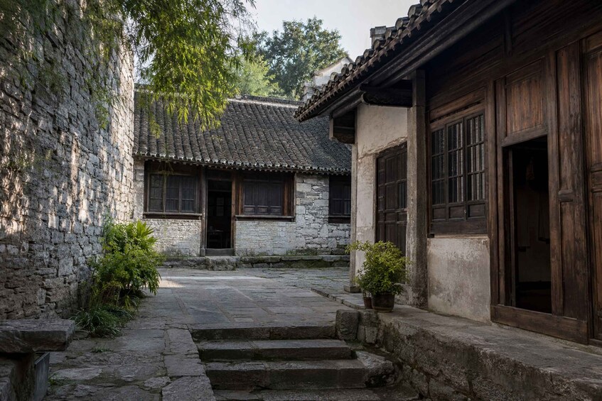 A traditional courtyard with stone walls, wooden doors, and tiled roofs. 3