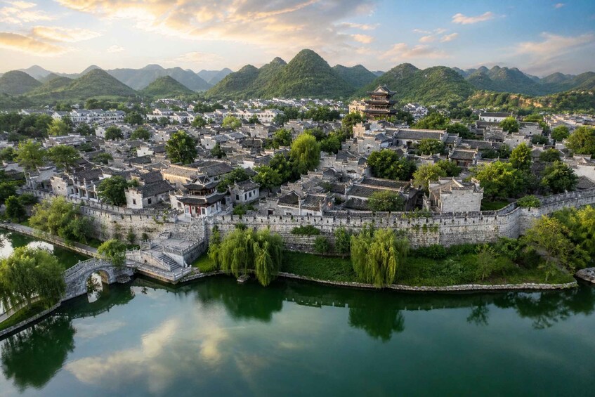 A traditional Chinese town with historic architecture, a river, and surrounding mountains. 1