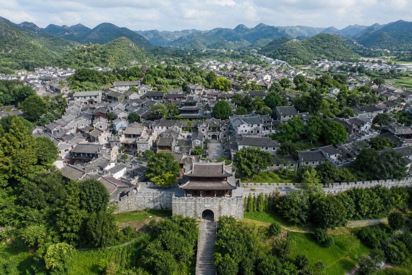 A traditional Chinese village with a prominent gate and surrounding mountains. 4