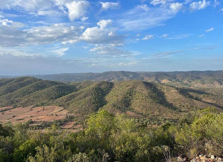 Un paysage montagneux, avec des collines douces et une végétation clairsemée, sous un ciel partiellement nuageux. 4