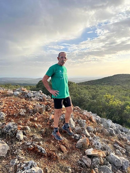 Une personne se tient debout sur un promontoire rocheux, avec un paysage montagneux en arrière-plan. 1
