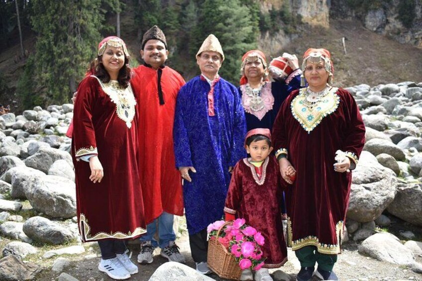 A group of people in traditional attire standing on rocky terrain with a mountainous backdrop. 5