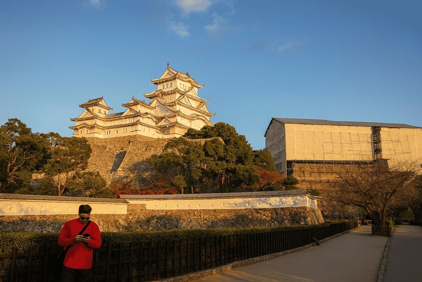 A traditional Japanese castle with multiple tiers and a modern building in the foreground. 5
