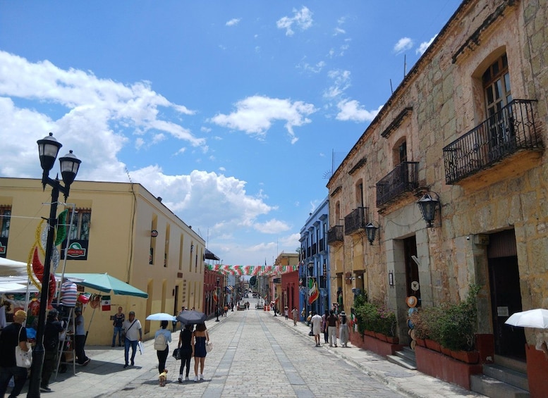 A cobblestone street lined with historic buildings, a street vendor, and people walking. 1