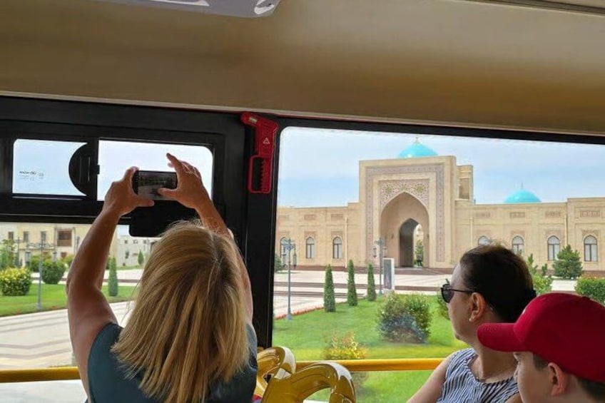 A person taking a photo of a building with a large archway and domes. 5